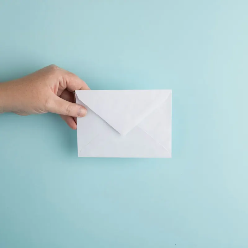 A hand holding a plain white envelope