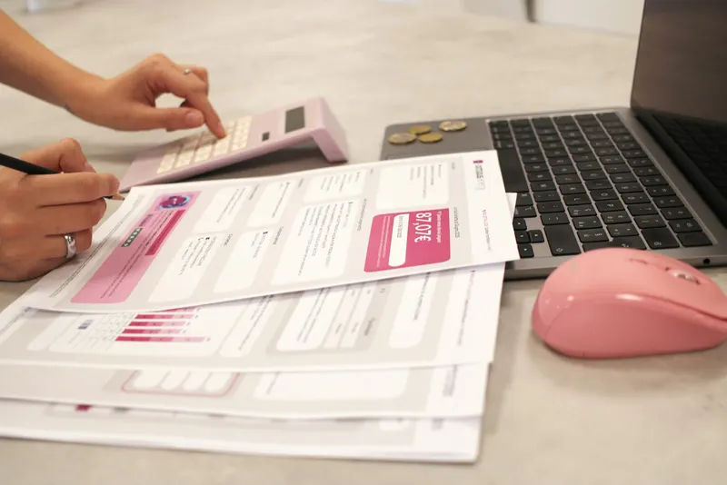 Hands sorting receipts and bills next to a calculator